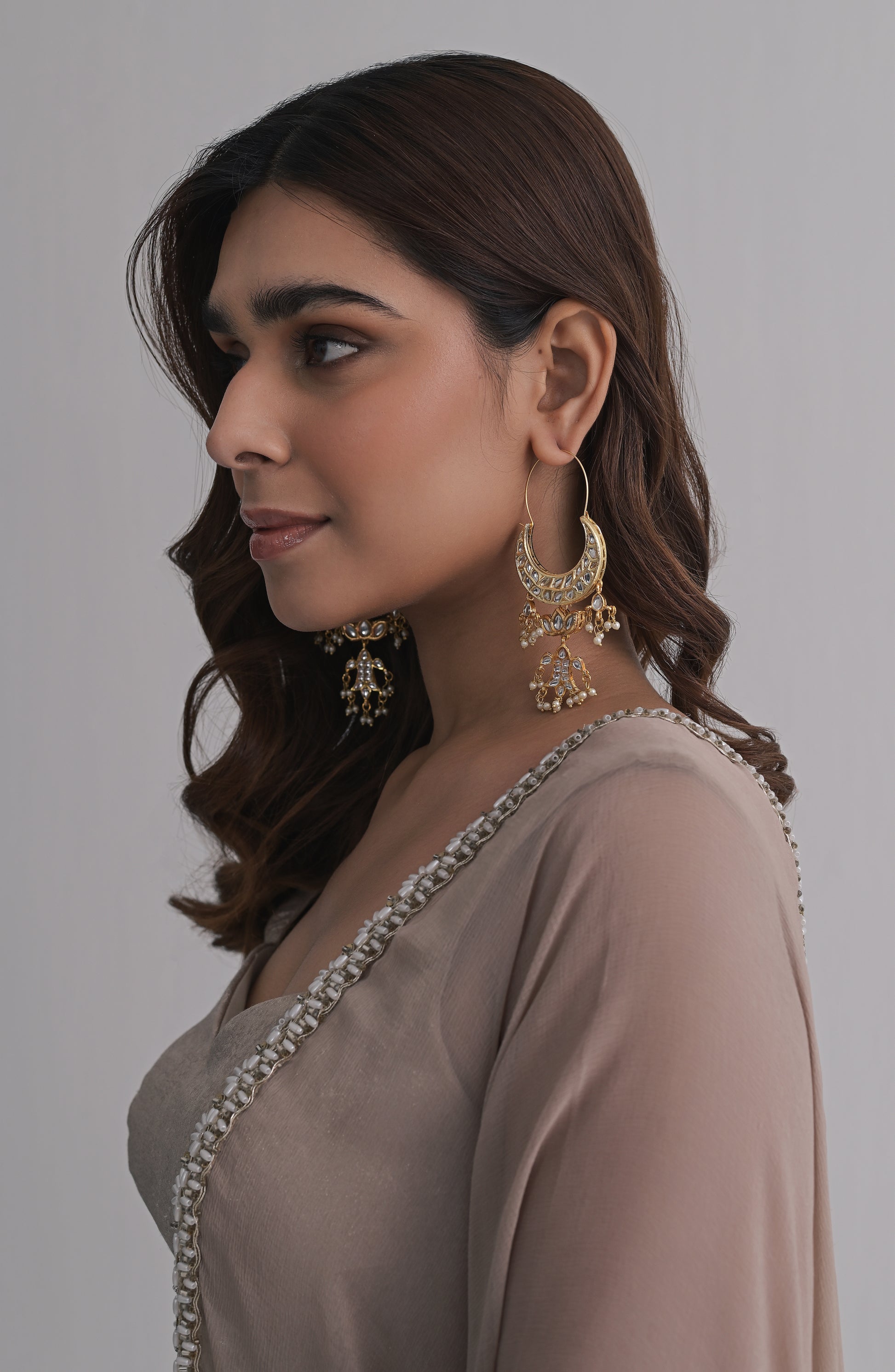 Oversized gold Chandbali earrings with mirror-finished stones, a central lotus motif, dangling jhumka-style elements, and pearl accents.