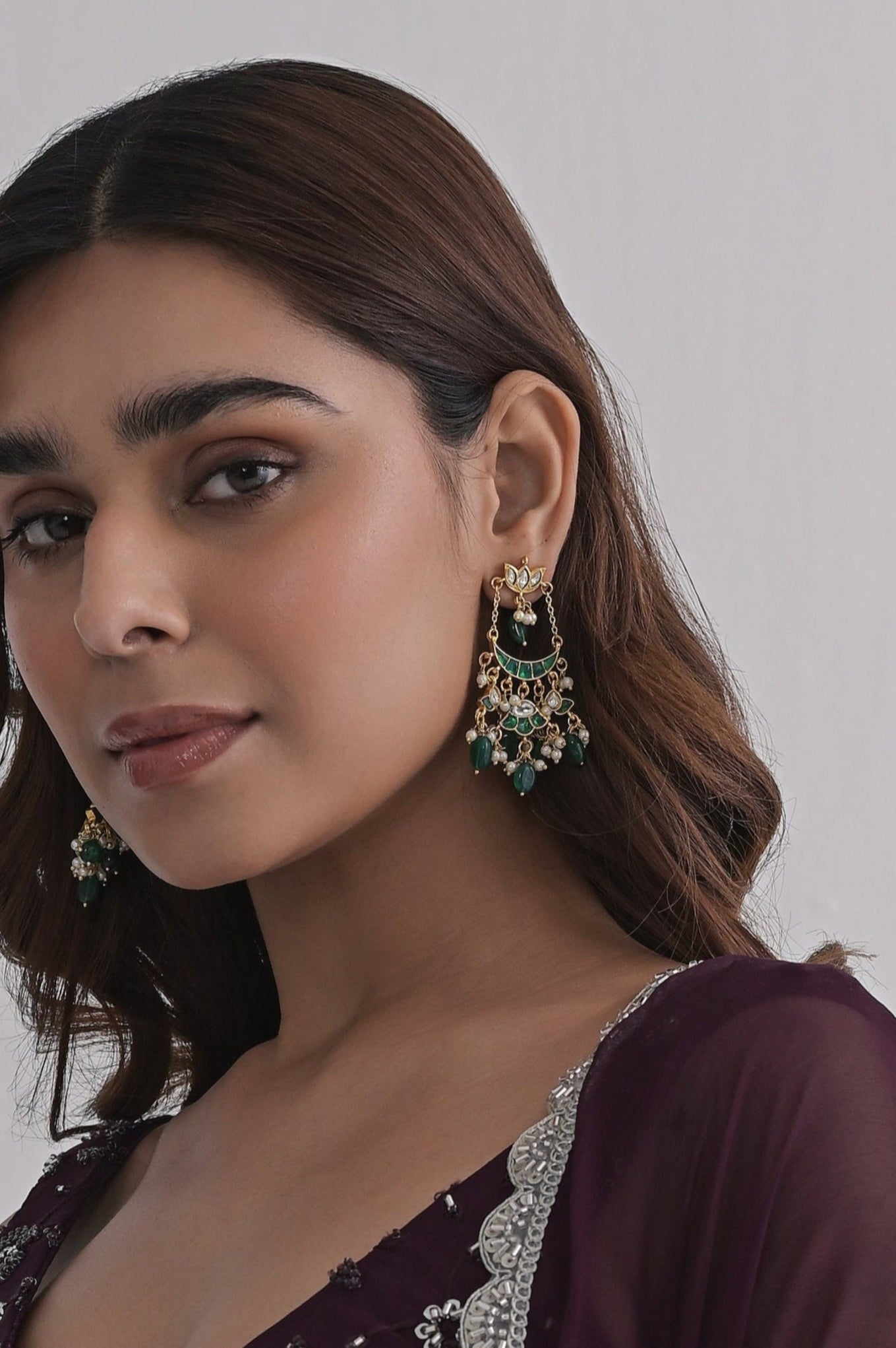 Small gold-toned Chandbali earrings with a crescent design, green enamel detailing, and delicate pearl and bead drops.