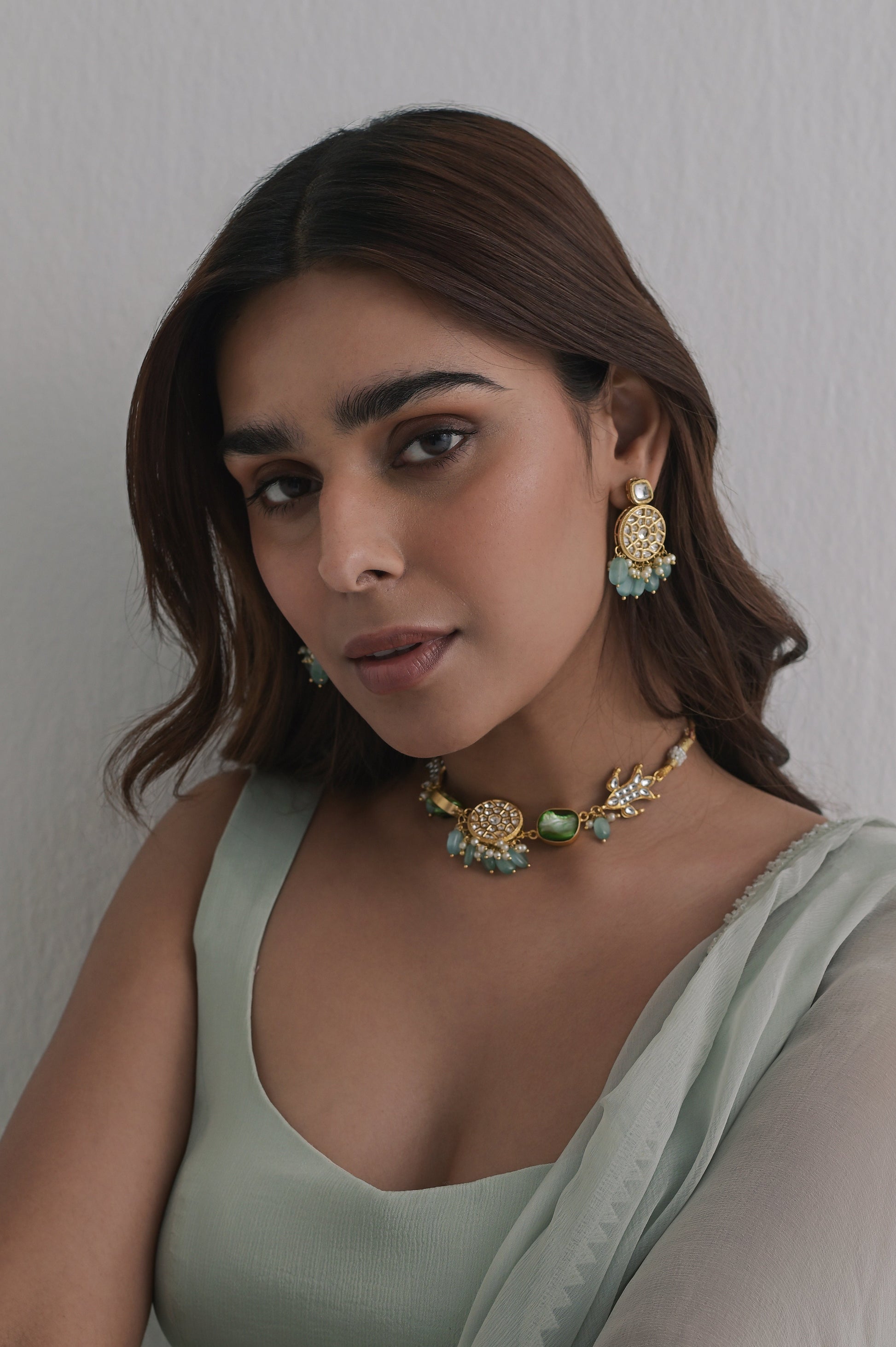 Handcrafted gold-toned jewelry set with round kundan-studded motifs, and soft green Monalisa stones. Includes necklace and earrings.