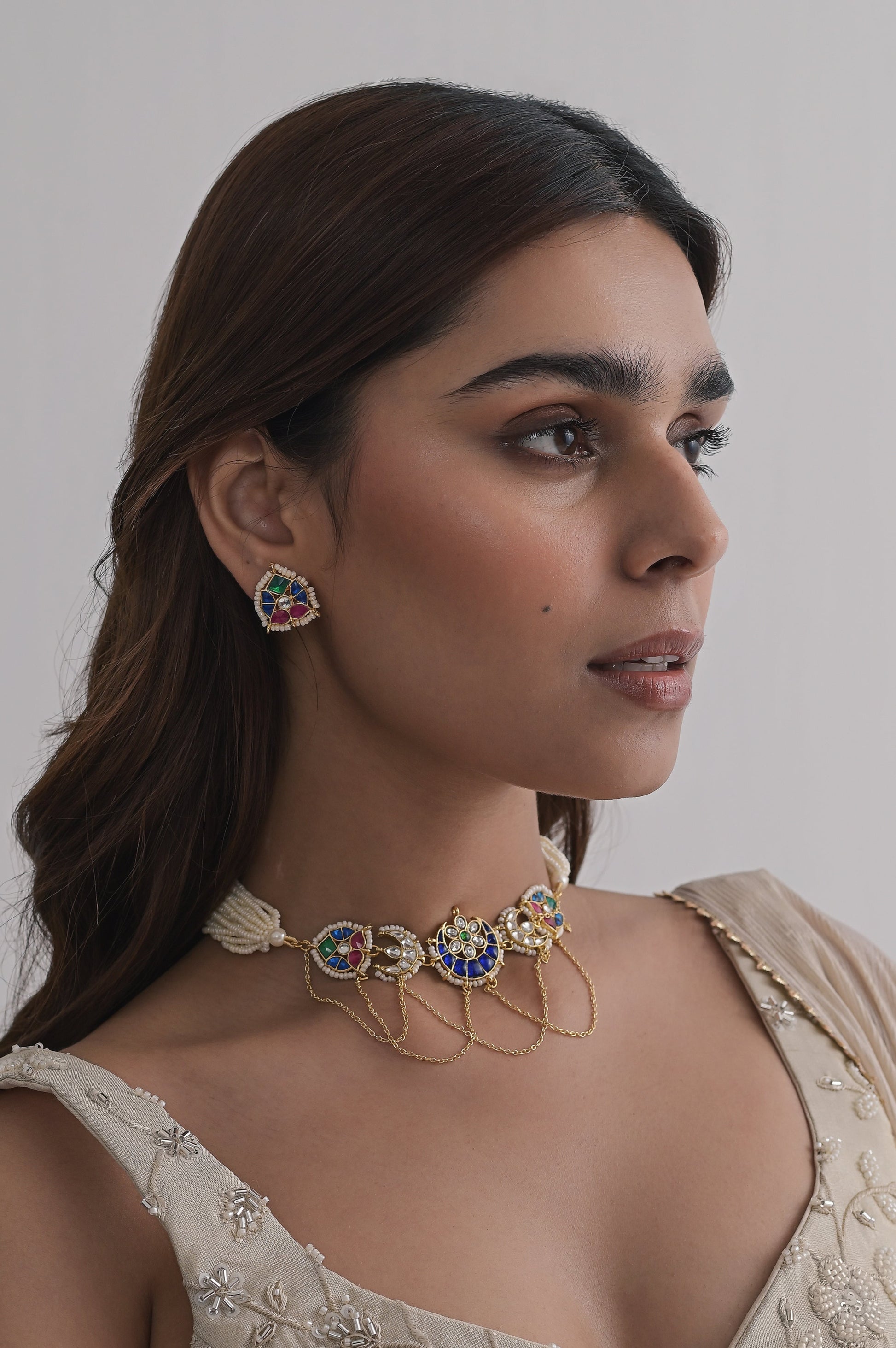 Gold choker set with royal blue enamel, crescent and floral motifs, kundan stones, pearl accents, and layered gold chains, paired with matching stud earrings.